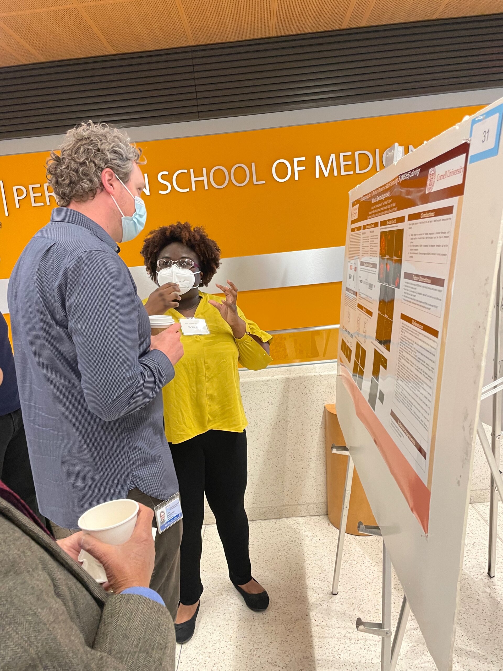 A Cornell graduate student describes her research results to a faculty member in front of her scientific poster display
