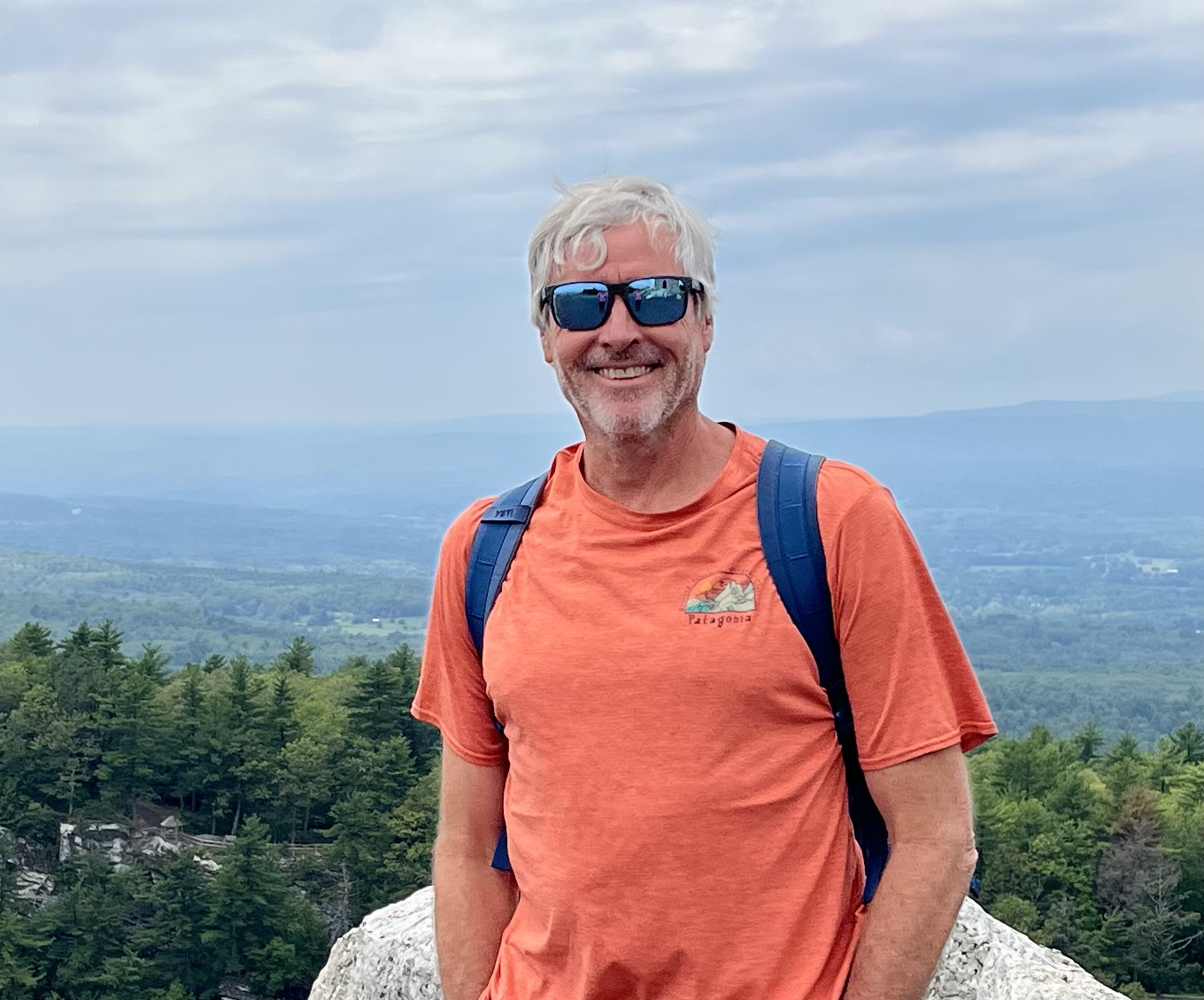 Dr. Lansford wearing sunglasses, smiling at the top of a scenic overlook